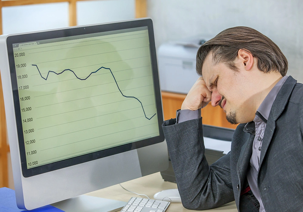 Common Investment Mistakes to Avoid for Smarter Investing 2 Frustrated businessman looking at declining stock chart on computer screen
