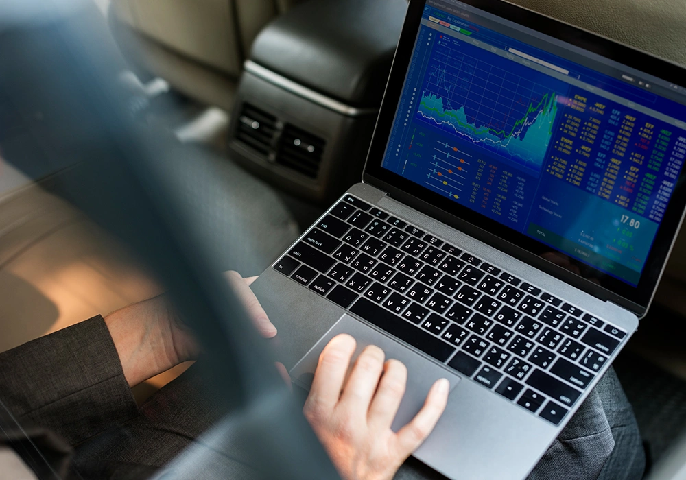 How to Use Leverage in Crypto Trading Without Increasing Risk 2 Person working on a laptop with forex trading charts displayed in a car.